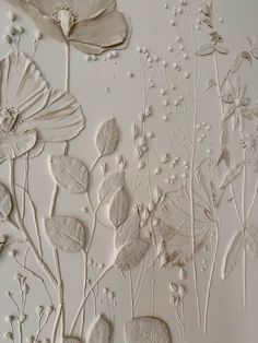 some white flowers and leaves are on a wallpapered surface in an art gallery