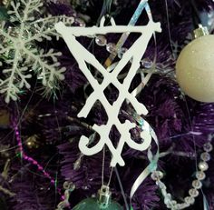 a white ornament hanging from the side of a purple christmas tree with snowflakes