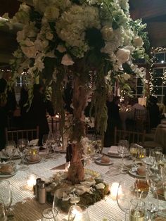 a tall centerpiece with white flowers and greenery