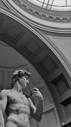 black and white photograph of a statue in front of a building with a skylight