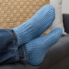 a person with blue socks and jeans sitting on a couch