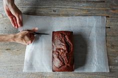 a person cutting a loaf of bread on top of a piece of paper with a pair of scissors