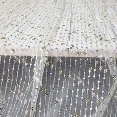 the sheer fabric has beads on it and is white with green, yellow and blue dots