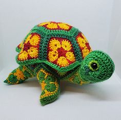 a crocheted turtle sitting on top of a white table next to a wall