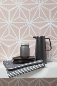 a table with plates and cups on it next to a wallpapered pattern that looks like hexagonal tiles