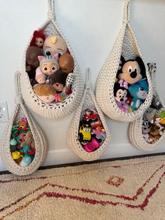 three hanging baskets filled with stuffed animals on top of a carpeted floor next to a wall