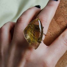 Make a statement and give the gift of clarity with our Rutilated Quartz Ring. This exquisite piece showcases the unique beauty of rutilated quartz, known for its delicate golden needles and powerful energy. It's more than a statement piece; it's a meaningful gift that captures the essence of insight and elegance. 🔸Adjustable band ring 🔸30 mm stone size 🔸Color may vary according to lighting 🔸Silver filled We offer  🔸Fast shipping  🔸Free shipping for eligible orders  🔸Polishing cloth  🔸Fre Unique Clear Crystal Ring As A Gift, Unique Clear Crystal Ring For Gift, Handmade Citrine Crystal Ring As Gift, Unique Crystal Ring With Large Stone As Gift, Unique Crystal Ring With Large Stone For Gift, Handmade Amber Crystal Ring For Gift, Handmade Amber Crystal Ring Gift, Quartz Jewelry Ring Gift, Quartz Ring Jewelry For Gift