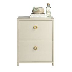 a white nightstand with two drawers and a bottle on top