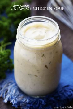 a glass jar filled with chicken soup sitting on top of a blue towel next to some parsley