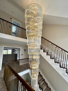 a large chandelier hanging from the ceiling in a room with stairs and railings