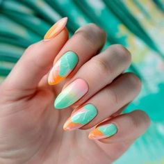 a woman's hand with green, orange and white nails