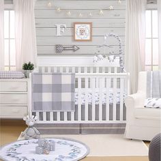 a baby's room is decorated in white and gray colors with plaid blankets on the crib