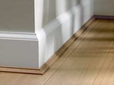 an empty room with white walls and wood floors, the floor is shiny from the sun