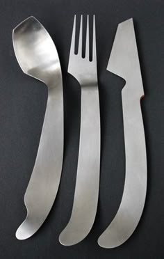 three forks and two knives on a black surface