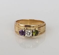 "A beautifully uniquely designed vintage, diamond, peridot and amethyst three stone solid gold ring. The three vibrant gemstones are set superbly within a solid, white gold gallery. With a lovely motif to the band. The stones compliment each other wonderfully, with excellent sparkle and vibrancy in all light conditions. There is a lovely inscription to the inside of the ring which reads \"heartbeat\". This piece is very unique, perfect for a special occasion for someone very special. ▪ Overall Condition: Excellent ▪ Metal: 14ct Gold ▪ Gem: Diamond 20.ct ▪ Gem Clarity: SI ▪ Gem Colour: I ▪ Gem: Peridot ▪ Gem Clarity: Excellent ▪ Gem Saturation: Very Good ▪ Gem Colour: Mid Green Hue ▪ Gem: Amethyst ▪ Gem Clarity: Excellent ▪ Gem Saturation: Very Good ▪ Gem Colour: Purple ▪ Ring Size UK: M 1/ Three Stone Diamond Gemstones For Anniversary, Green Three Stone Gemstones For Anniversary, Gold Three Stone Gemstones For Anniversary, Anniversary Multi-stone Peridot Gemstones, Vintage Three Stone Birthstone Ring For Anniversary, Fine Jewelry Amethyst Three Stone Ring For Anniversary, Amethyst Three Stone Ring For Anniversary, Three Stone Amethyst Ring For Anniversary, Gold Three-stone Amethyst Ring For Anniversary