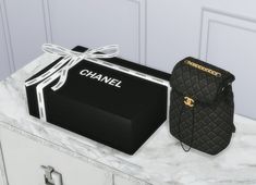 a black chanel bag sitting on top of a marble counter next to a box