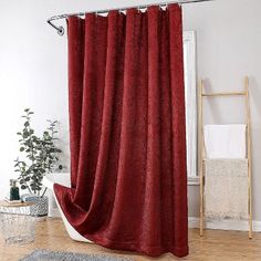 a red shower curtain in a bathroom next to a white bathtub and wooden floor