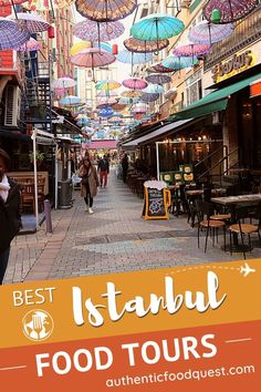 an alleyway with umbrellas hanging from the ceiling and people walking on the sidewalk