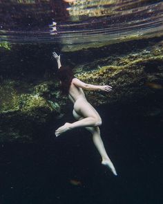 a naked woman is swimming in the water