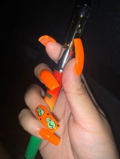 a person holding an orange and green pen with cartoon faces on the top of it