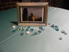 there is a picture frame on top of a table with jewels scattered around it and the picture in the middle