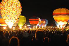 many hot air balloons are lit up at night