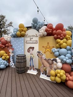 an outdoor display with balloons and paper cutouts on the ground, including a cowboy theme