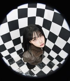 a woman with black hair is standing in a checkered room