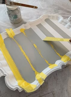 a tray that has been painted yellow and gray with some tape on the edges, sitting on top of a table