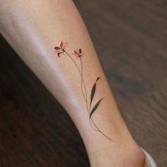 a small flower tattoo on the left ankle and right leg, with green stems growing out of it