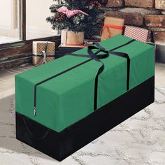 a large green present box sitting in front of a christmas tree