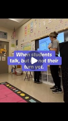 two people standing in front of a classroom with a video game on the wall behind them that says when students talk, but not their turn yet