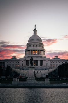 the capitol building is lit up at night with pink clouds in the sky above it