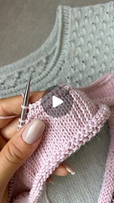 a woman is holding a knitted sweater and crochet scissors in her hand