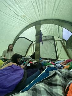 a group of people laying in a tent with sleeping bags on the ground next to them