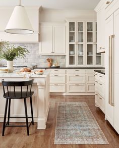 a kitchen with white cabinets and an area rug on the floor in front of it