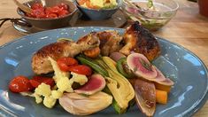 a blue plate topped with meat and veggies on top of a wooden table