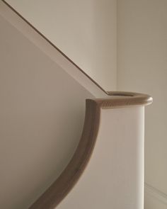 the corner of a white wall with a curved wooden handle on it's side