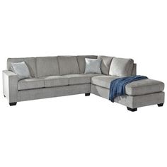 a gray sectional couch with pillows on it and a blue throw blanket in the corner