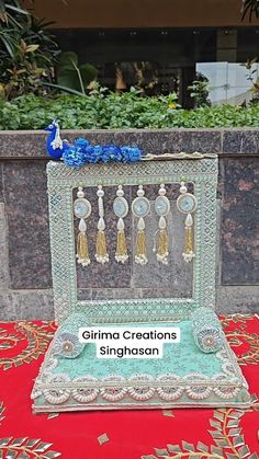 an elaborate display case with tassels and beads in it on a red table cloth