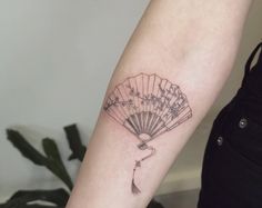 a woman's arm with a fan tattoo on it