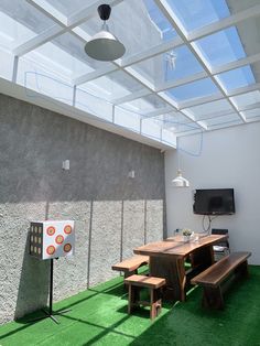 an outdoor dining area with green grass and skylights above the table, television on wall