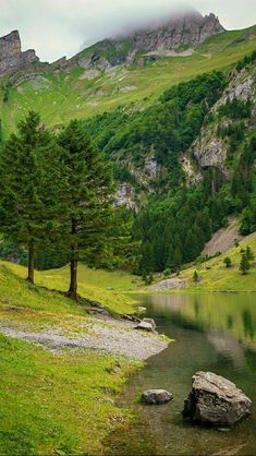 there is a small lake in the middle of this mountain range with trees on it