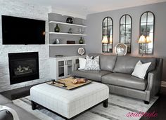 a living room with gray couches and white fireplace