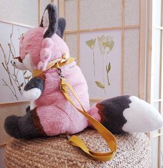 a stuffed animal is sitting on top of a basket with a leash around it's neck