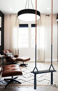 a living room with leather chairs and a hanging swing in the middle of the room