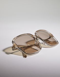 Timeless Reflections low bridge glasses in acetate and titanium The transparent effect of the acetate accentuates the oversized square lines of these frames, which are made in Japan. Details of impeccable craftsmanship stand out on the slim titanium temples: the faceted texture is revealed in an interplay of sparkling reflections that evoke the iconic codes of Brunello Cucinelli women's collections. The fit is specially designed for faces with a low nose bridge. The frame is part of the "Timeless Reflections" line, inspired by Brunello Cucinelli's timeless codes of feminine elegance. The details that stand out on the temples recall sparkling monili reflections, an iconic element of the Women's Collections. Chic Clear Sunglasses With Square Frame, Chic Clear Square Frame Sunglasses, Formal Clear Glass Sunglasses, Elegant Acetate Square Frame Sunglasses, Elegant Square Frame Acetate Sunglasses, Clear Acetate Sunglasses With Uva Protection, Luxury Clear Square Frame Sunglasses, Elegant Sunglasses With Gradient Polycarbonate Lenses, Titanium Glasses