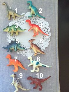 a group of toy dinosaurs sitting on top of a table next to a doily