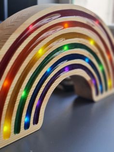 a close up of a rainbow shaped wooden object with lights on the top and bottom