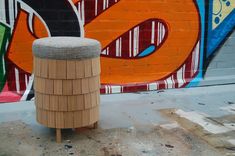 a wooden stool sitting in front of a graffiti covered wall with an odd design on it